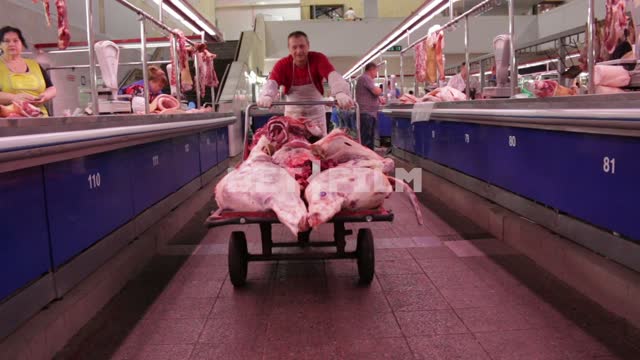 The butcher carries the carcass on the truck through the market. butcher, meat, market, truck, a...