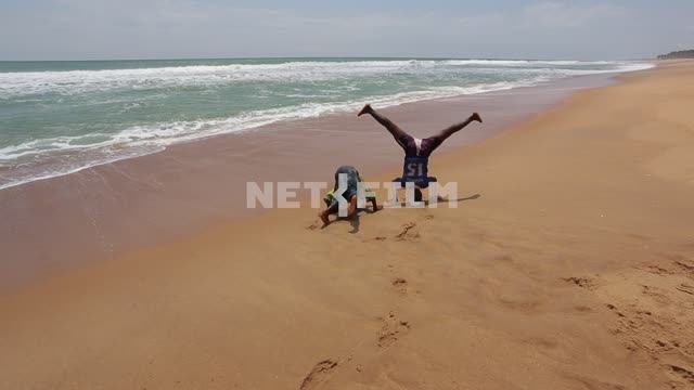 African children playing on the beach. African children, ocean, beach, children playing, headstand,...