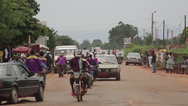 Дорога в небольшом городке, африканцы в сиреневой униформе, ухабы на дороге, мотоциклы Дорога в...