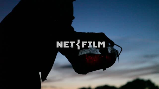 Man pours brown liquid from the bottle.
Night, field, sky, man, silhouette, a clear silhouette,...