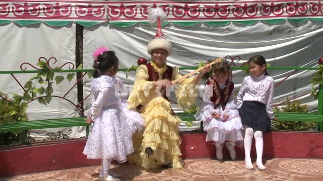 Молодая казахская женщина с нарядными детьми играет на кобызе и поет Молодая казахская женщина с...