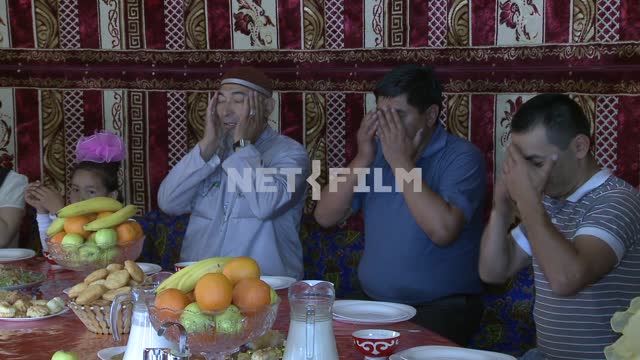Многочисленная казахская семья молится в юрте перед  едой Многочисленная казахская семья молится в...