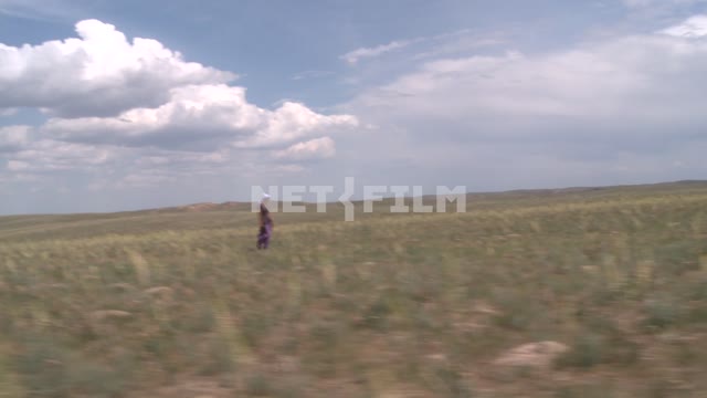 The girl is on the steppe mountains in the background, followed by other people. The girl is on the...