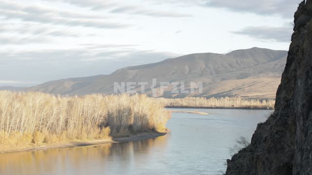 The shore of the wide river with yellow autumn vegetation, mountains in the distance.
Sky, clouds,...