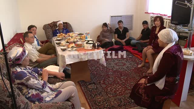 Казахская семья сидит за столом Казахская семья сидит за столом. Казахстан, застолье, этнография