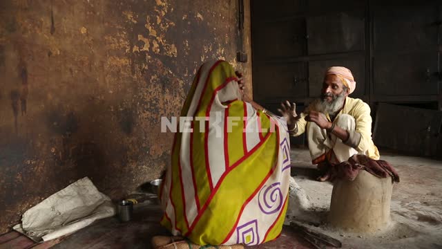 Indian woman and old Indian crematorium sitting talking animatedly Indian woman, Indian man,...