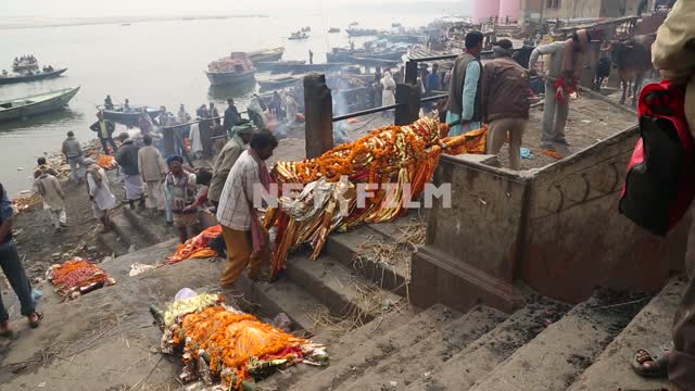 on the banks of the Ganges on the stone steps, dead men on the bamboo stretchers, the Indian men...