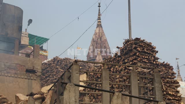on the backdrop of the Indian temple folded on the stone steps wood for the pyre Indian temple,...