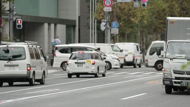 Токио. Япония. Улица. Едут машины. Люди переходят дорогу. Выход через расфокус. Токио. Япония....