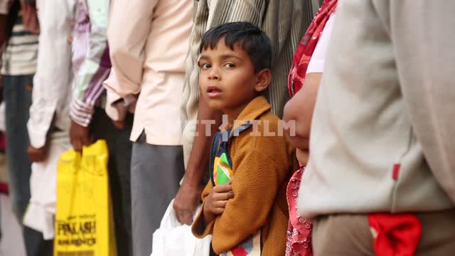 an Indian boy stands in line, looking at the camera Indian boy, place, exoticism, Ethnography