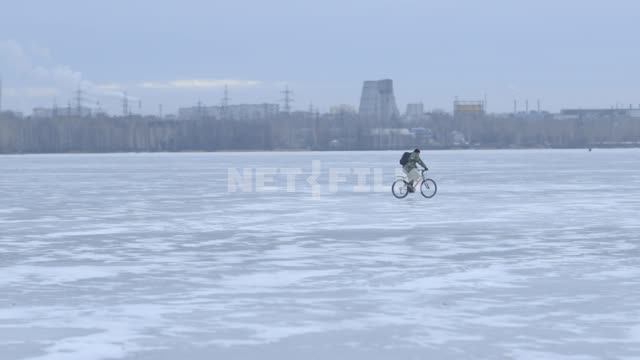 Замерзшая река. Камера следует за велосипедистом, который едет по льду. Россия, Екатеринбург, зима,...