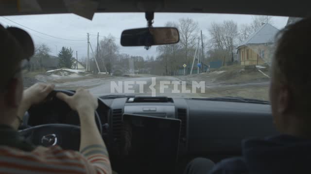 Вид из кабины. Двое мужчин въезжают на машине в русскую деревню. Ранняя весна, весна, Россия,...