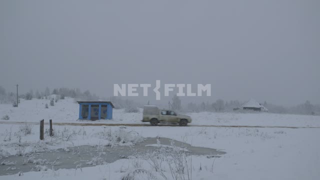 Белая машина проезжает мимо голубой остановки. Заснеженная деревня, Россия,  снег, снегопад,...