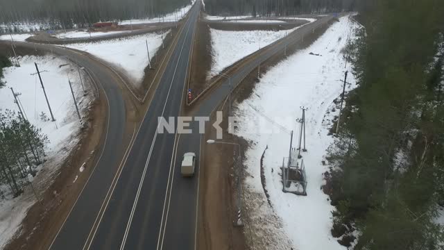 Shooting from above.
White car driving on a road in a snowy pine forest and arrives at a fork.
Go...