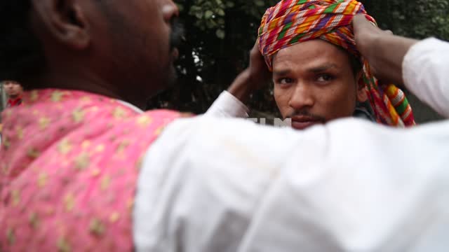 Молодой индийский мужчина наматывает парню чалму на голову Молодые люди, чалма, индусы