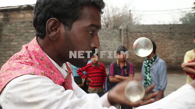 Street fakir shows tricks with transparent balloons for the kids on a little street Street fakir,...