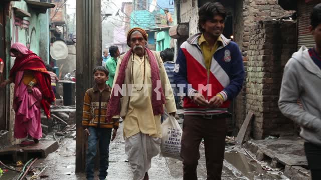 Люди идут по улице в индийских трущобах Люди, бедняки, индийские трущобы