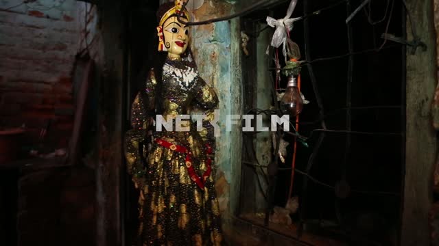 Кукла-индианка качается на нитках на фоне ободранной стены Кукольный театр, трущобы, женская кукла...