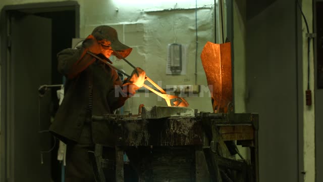 Caster with tongs works in a factory The foundry Plant the Foundry