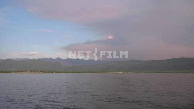 Вид с катера на берег озера Байкал, тайгу и Баргузинский хребет, в небе дым от лесного пожара...
