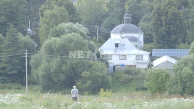 Man goes to the Church through the overgrown meadow.
Russia, summer, village, Church, village,...