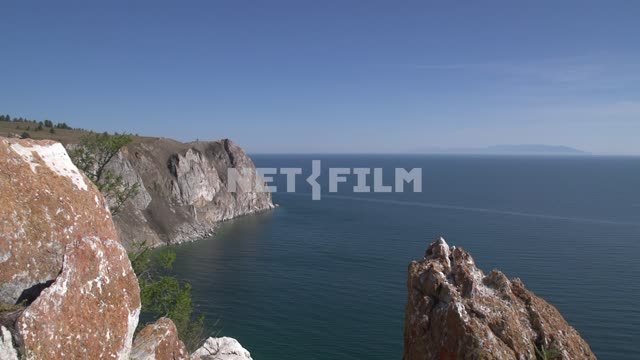 Скалистый берег острова Ольхон, камни, покрытые лишайником ярко-красного цвета Россия, Сибирь,...