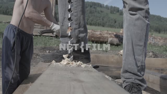 Slow motion, close-up.
Drill a hole in the tree in the background of a man hammering a...