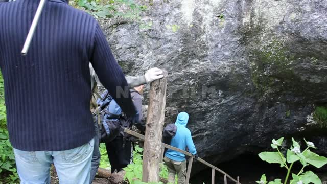 Askinskaya cave, tourists with headlamps descend to the entrance of the cave by a wooden staircase...