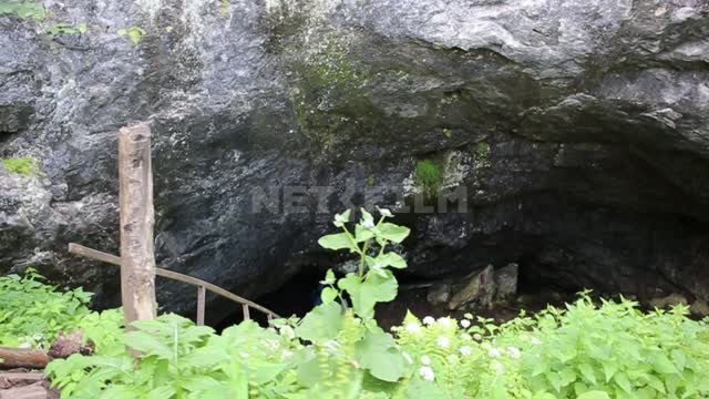 Askinskaya cave, tourists with headlamps go down to the entrance of the cave by a wooden staircase,...