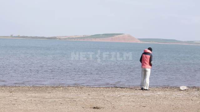 Lake Aslikul (Asylykul), a man stands on the shore Lake, Water, pond, waves, hills, shore, sand,...