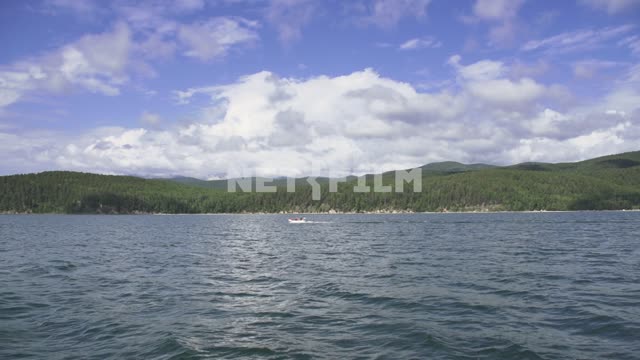 View from the boat on the shore of lake Baikal, summer landscape, mountains covered with forests...