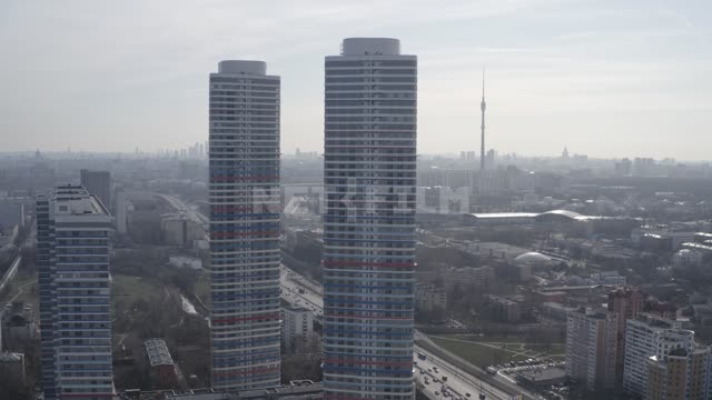 Two high-rise buildings in the background tower "Ostankino", the roofs of houses and the busy urban...