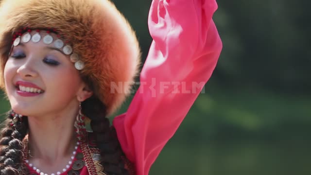 A girl in a national costume dances on the river bank, face close-up Ural, Salavatsky district,...