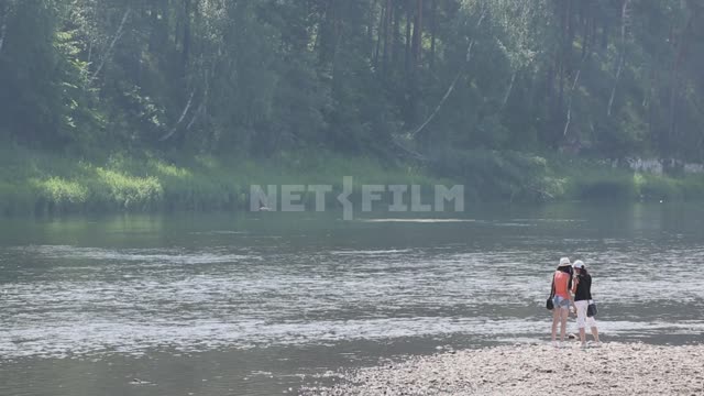 Люди гуляют на мелководье, две девушки стоят на краю воды, две проходят мимо Урал, Салаватский...