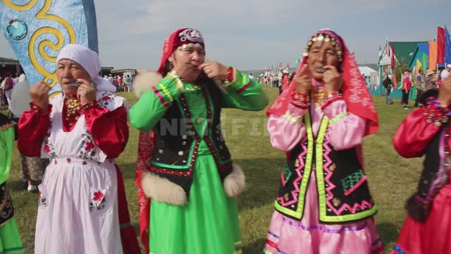 Национальный праздник, выступает фольклорный ансамбль, люди играют на народных музыкальных...