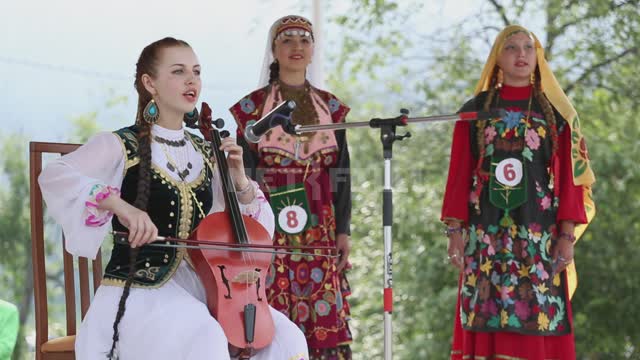 Национальный праздник, на сцене фольклорный ансамбль, девушка играет на кыл-кубызе и поет Урал,...