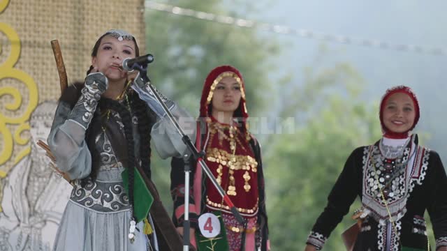 Национальный праздник, на сцене фольклорный ансамбль, девушки играют и поют Урал, Салаватский...