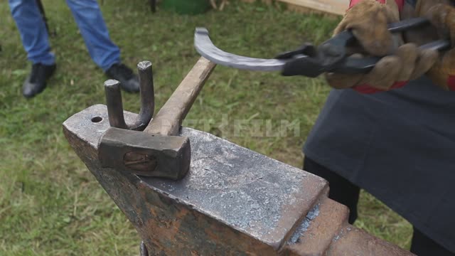 A blacksmith works on an anvil, making a horseshoe Ural, Salavatsky district, holiday, fair,...