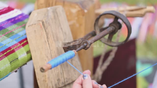 A woman works on a hand loom, winds a thread on a shuttle Ural, Salavatsky district, holiday, fair,...