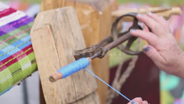 A woman works on a hand loom, winds a thread on a shuttle Ural, Salavatsky district, holiday, fair,...