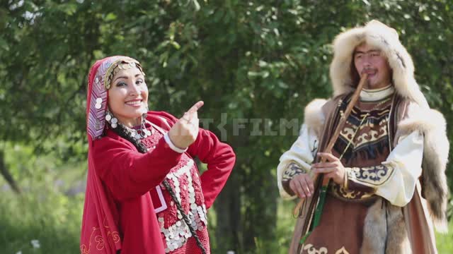 A man plays a folk wind instrument, a woman dances Ural, Salavatsky district, holiday, national...