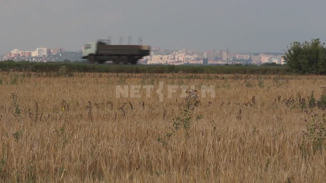A field, a view of the city, a truck passes along the road Ural, field, crop, grain crops,...