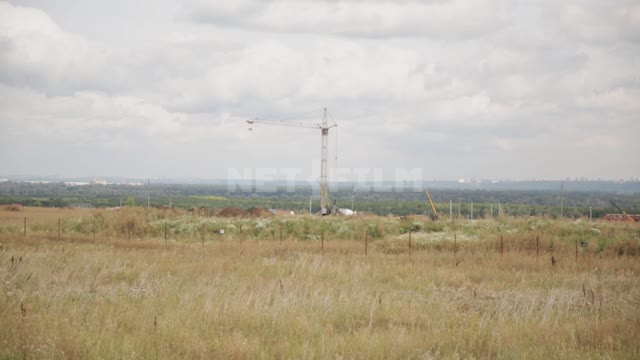 A tower crane in the middle of a field Field, construction site, construction, fencing, crane,...
