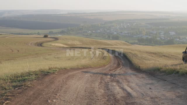 Проселочная дорога, по обочине едет легковой автомобиль Урал, поля, дороги, автомобили, холмы,...