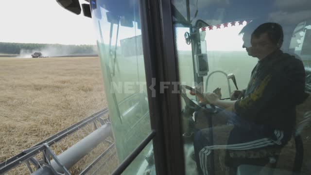 Комбайн работает в поле, уборка урожая, водитель в кабине Урал, поле, урожай, зерновые культуры,...