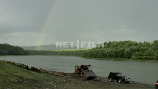 The car on the river Bank.
Rainbow in the distance Coast, river, trees, forest, hills, car,...