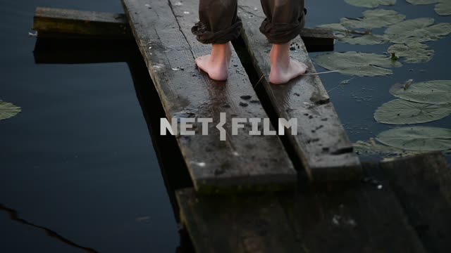 A man with a fishing rod on a wooden bridge Fishing, bridge, water, water lilies, feet