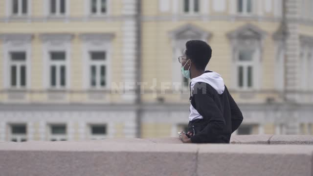 Молодой человек в защитной маске на фоне старинного здания в центре Москвы Африканец, карантин,...