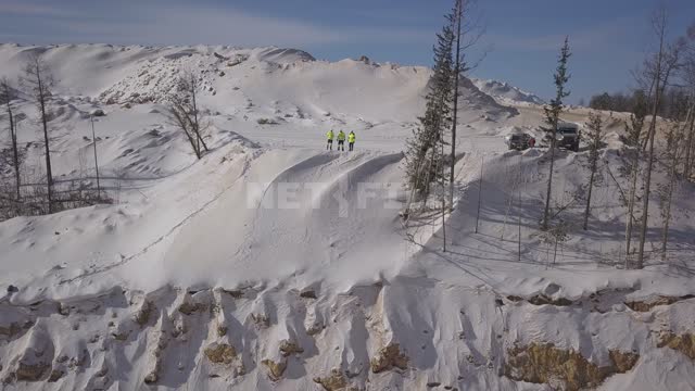 Gold mining, workers in bright overalls stand on the edge of a gold mining pit Gold mine, quarry,...