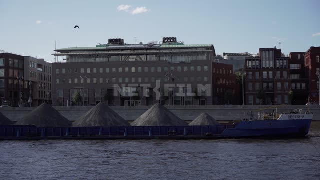 On the river there is a cargo barge, it is overtaken by a pleasure boat Moscow-river, embankment,...